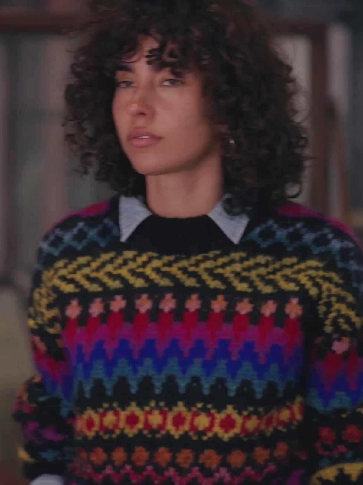 Video of a woman wearing a colorful sweater over a chambray shirt