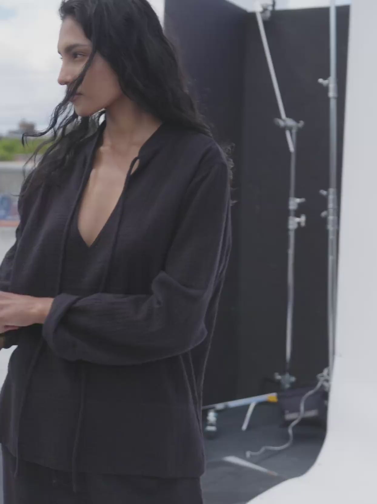 Video of a woman wearing a black gauze top and matching pants on a photo set