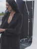 Video of a woman wearing a black gauze top and matching pants on a photo set