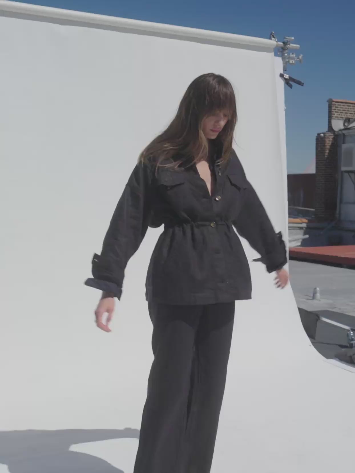 Video of a woman wearing a black linen jacket and matching pants against a white background