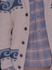 A man wearing a cream graphic cardigan over a button up shirt 