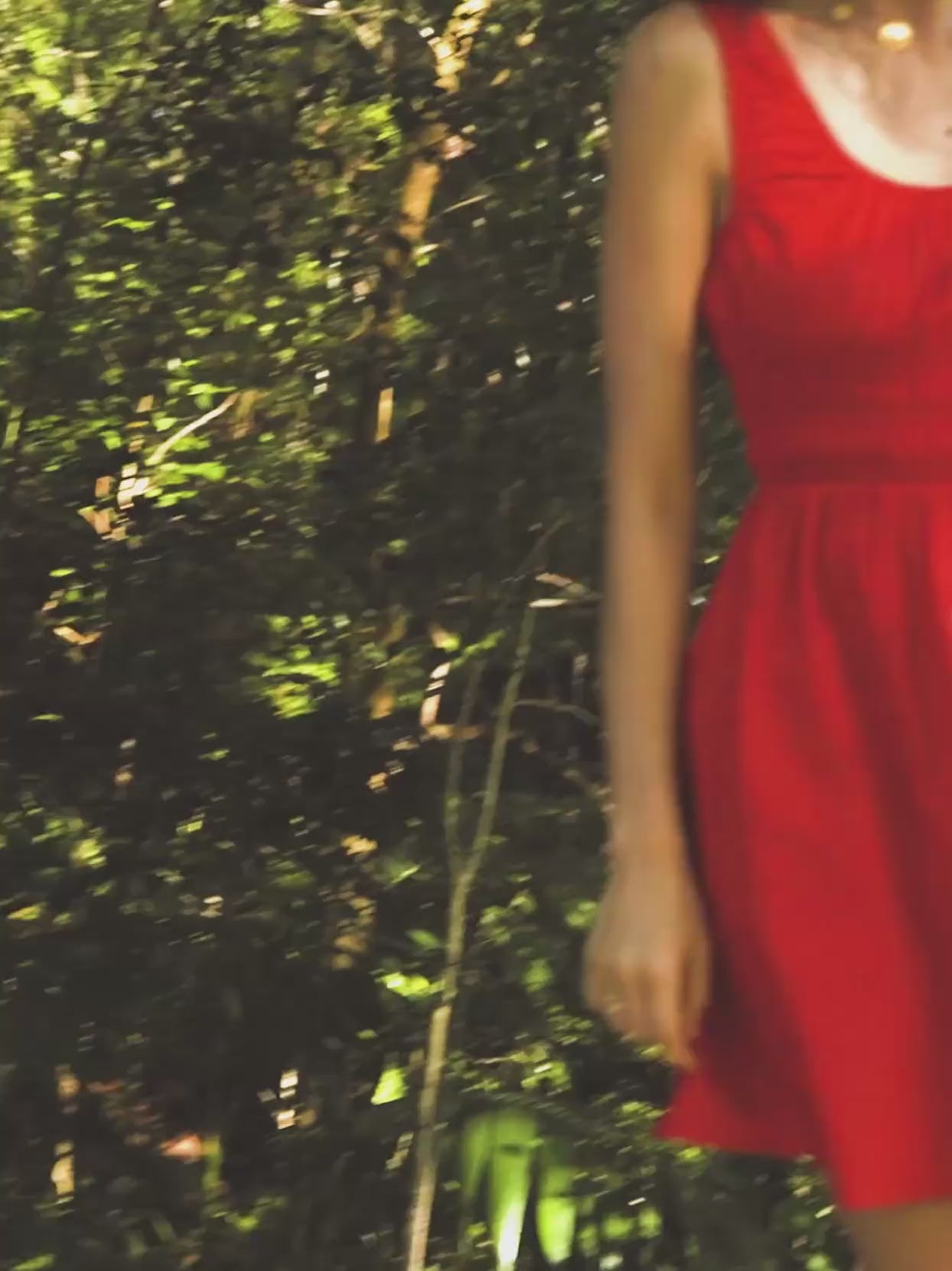 Video of a woman wearing a red mini dress in a forest setting